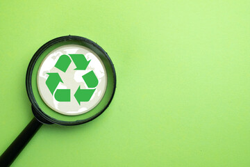 Recycling and environmental protection concept. A magnifying glass focuses on a green recycle...