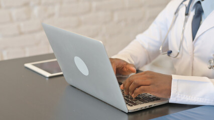 Close up of African Male Doctor Typing on Laptop