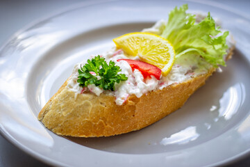 Fresh baguette with crab spread, garnished with parsley, red pepper, lettuce, and a lemon slice....