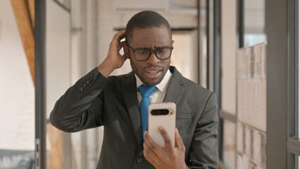 Portrait of African Businessman Shocked by Loss on Phone