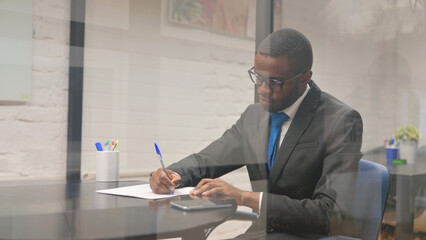 Fototapeta premium African Businessman Writing a Letter at Workspace