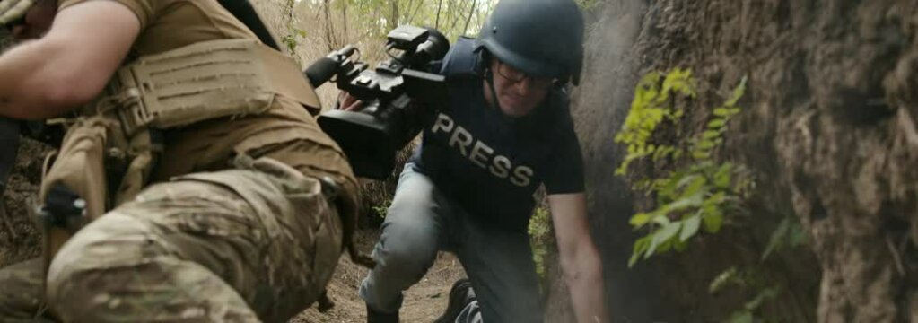 Interview in a war zone, suddenly shelling starts. Concept of war journalism, work of media in a conflict zone, danger on the front line.