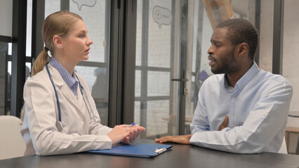Middle Aged Doctor Talking with Patient in Clinic