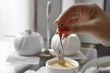 Young woman's hands in a cup of coffee