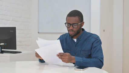 Middle Aged African Man Reading Annual Business Report of Company