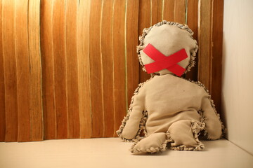 A doll with a red ribbon in her mouth on a book background
