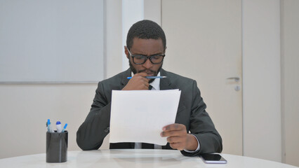 Thoughtful Businessman Reviewing Documents at office desk