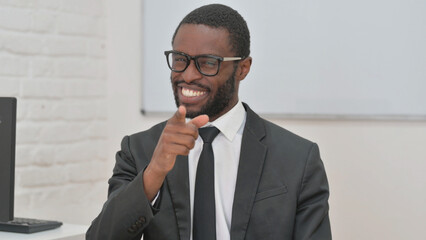 Smiling Young African Businessman Pointing at Viewer