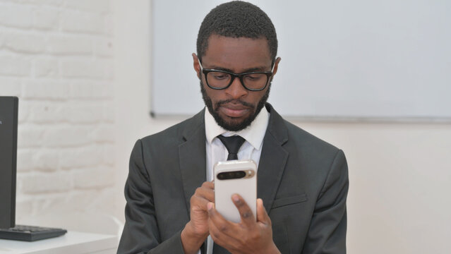 Focused Young African Businessman Using Smartphone