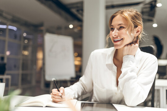 Professional woman working at modern desk with whiteboard in background