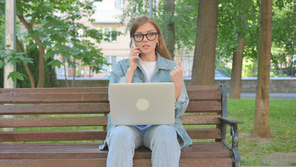 Woman Talking on Phone While Using Laptop while Sitting Outdoor
