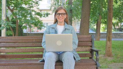 Casual Woman Smiling with Laptop while Sitting Outdoor