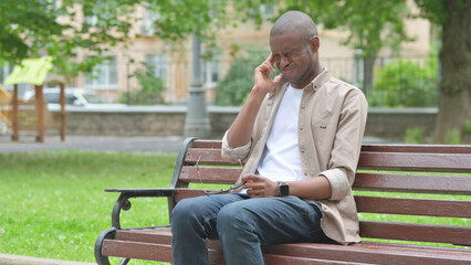 Fototapeta premium Young African Man Experiencing a Headache in the Park