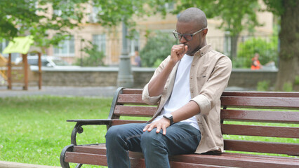 Obraz premium Sick Young African Man Coughing on a Park Bench