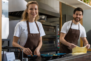 Man rolling dough working with woman in kitchen collaborating closely