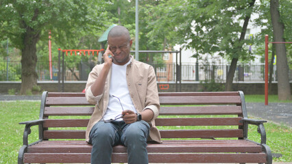 Fototapeta premium African Man with Headache Sitting Outdoor on Bench