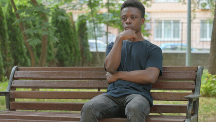 Obraz premium Casual African Man Pondering on a Park Bench