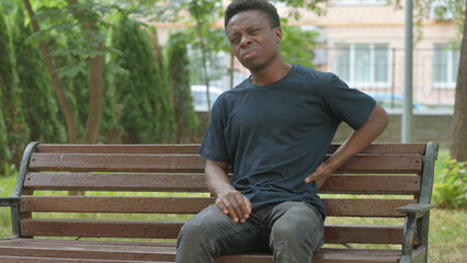 Obraz premium Casual African Man with Back Pain on a Bench
