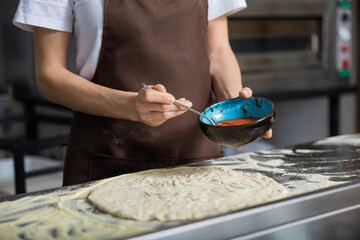 Woman spreads sauce pizza kitchen preparing meal care enjoying time