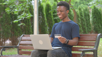Excited Casual African Man Doing Online Shopping in Park