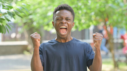 Excited Casual African Man with Fists Pumped Outdoors