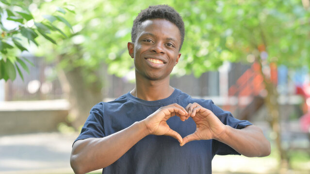 Casual African Man Making a Heart Gesture Outdoors