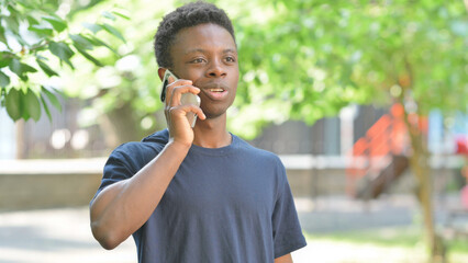 Casual African Man Talking on a Smartphone in a Park