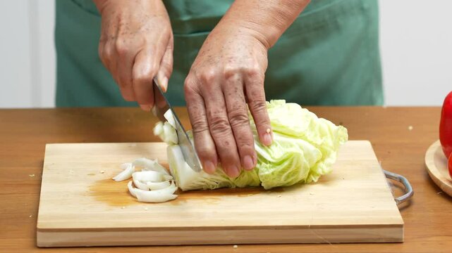 Closeup of male hands slicing Cabbage on a wooden board in the kitchen, preparing to cook.