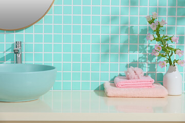 Mint basin, pink towel and fresh flowers create a cheerful spa-style bathroom. Aqua tiles and clean...