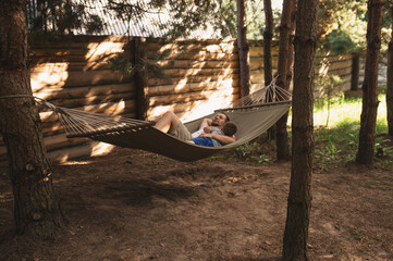 Father and son 5 years old fooling around playing relaxing in a hammock outdoors in a pine forest...