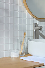 A Japandi-inspired bathroom corner with bamboo brushes, skincare jars, and a white sink. Soft...
