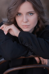 A female model poses sitting on a chair among nature and fields, an unusual photo of a summer Look