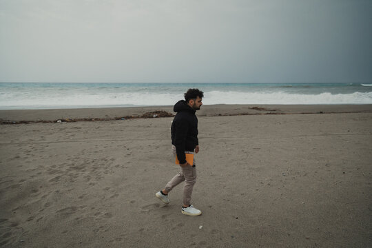 Man Arrives At The Sea On A Cloudy Day And Sits On A Boat To Read