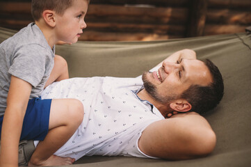 Father and son 5 years old fooling around playing relaxing in a hammock outdoors in a pine forest...
