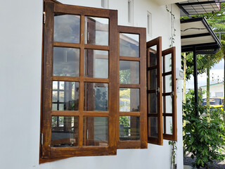 The view of the outer corner of the clean white-walled building shows dark brown wooden windows...