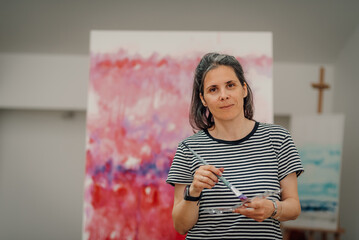 Female artist mixing colors on palette while painting abstract art in studio