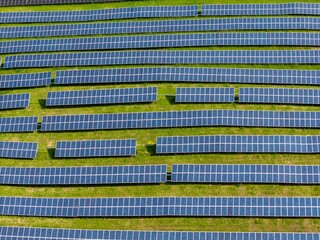 Aerial view of a solar farm with rows of solar panels on a green field