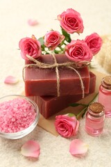 Soap bars, sea salt, essential oils and beautiful roses on beige table, closeup