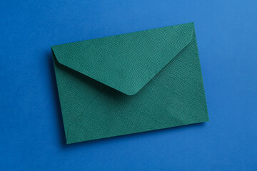 Beautiful invitation envelope on blue background, top view