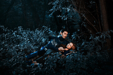 Fototapeta premium A scene depicting a medieval knight and maiden in armor and attire, embracing amidst a dimly lit forest. Represents fantasy, medieval romance, and the heartfelt connection between two individuals.