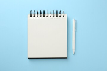 Notebook and pen a on light blue background, flat lay