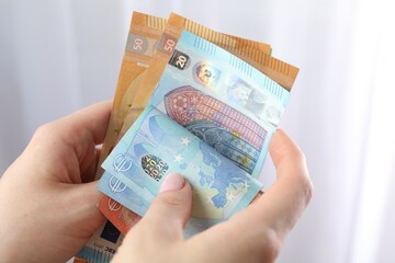 Woman counting euro banknotes indoors, closeup view