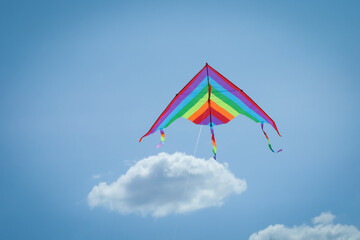 Colorful kite flying in blue sky, low angle view. Space for text