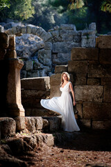 Young beautiful woman wering white dress at antique ruin