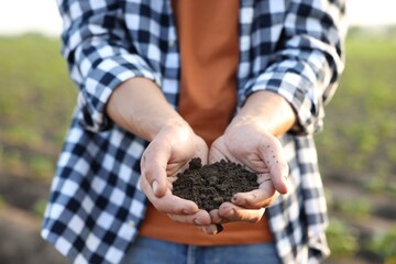 Man holding pile of soil in field, closeup