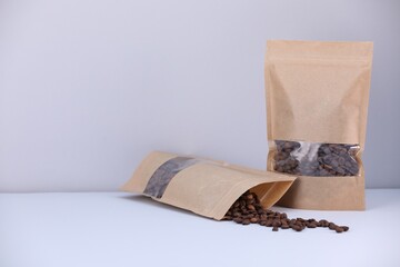 Zipper stand-up pouches with coffee beans on light grey background. Mockup for design