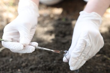 Scientist taking soil sample for research outdoors, closeup