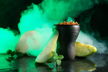 Hookah bowl with pear pieces, mint and smoke on black table, closeup
