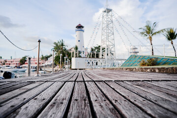 Wooden Boardwalk Leading to Lighthouse and Palm Trees in Tropical Marina