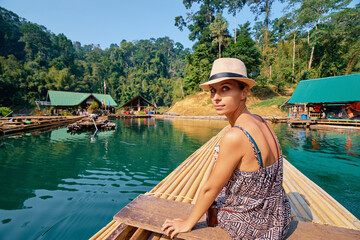 Woman Exploring Tropical River on Bamboo Raft Amid Scenic Jungle Landscape